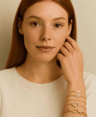 Bracelets dorés à motifs floraux et cœurs, portés par une femme avec une peau claire et des cheveux roux, symbole d'élégance et de style tendance dans la mode bijoux pour femmes.