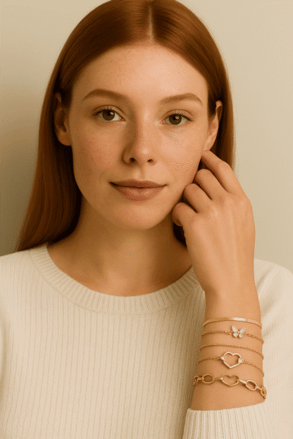 Bracelets dorés à motifs floraux et cœurs, portés par une femme avec une peau claire et des cheveux roux, symbole d'élégance et de style tendance dans la mode bijoux pour femmes.