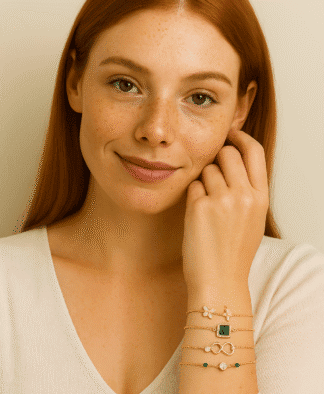 Bracelets en or avec pendentifs floraux, géométriques et à détails en émail vert, portés par une femme aux cheveux roux, mettant en valeur l'élégance et la sophistication des bijoux de mode pour femmes.