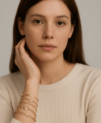 Bracelets en or avec pendentifs, tels qu'une petite fleur, un papillon et une chaîne à maillons, élégants et modernes, portés par une femme avec une peau claire et des cheveux bruns, style chic et sophistiqué, mode de bijoux femme.