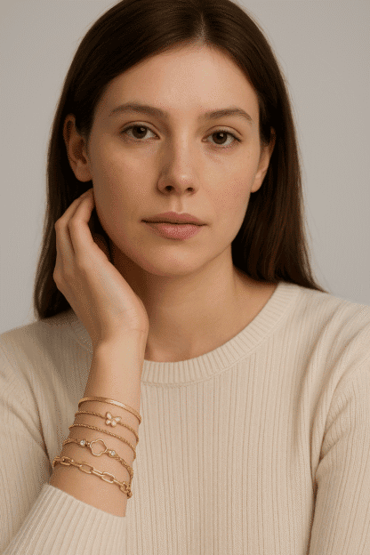 Bracelets en or avec pendentifs, tels qu'une petite fleur, un papillon et une chaîne à maillons, élégants et modernes, portés par une femme avec une peau claire et des cheveux bruns, style chic et sophistiqué, mode de bijoux femme.