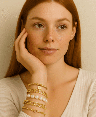 Bracelets en or et perles, style élégant et tendance, porté par une femme avec peau claire et cheveux roux. Accessoires parfaits pour un look chic et sophistiqué.