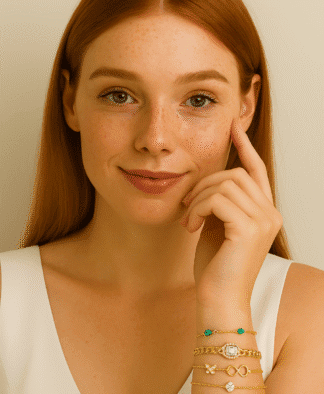 Bracelets en or avec pierres colorées et motifs variés, portés par une femme aux cheveux roux, peau claire et regard doux, pour une touche élégante et tendance à votre style de bijouterie fantaisie.